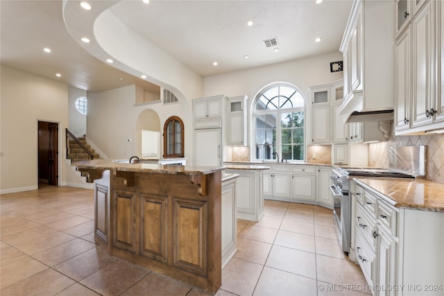 kitchen with high end stove, a center island, light stone counters, and white cabinets