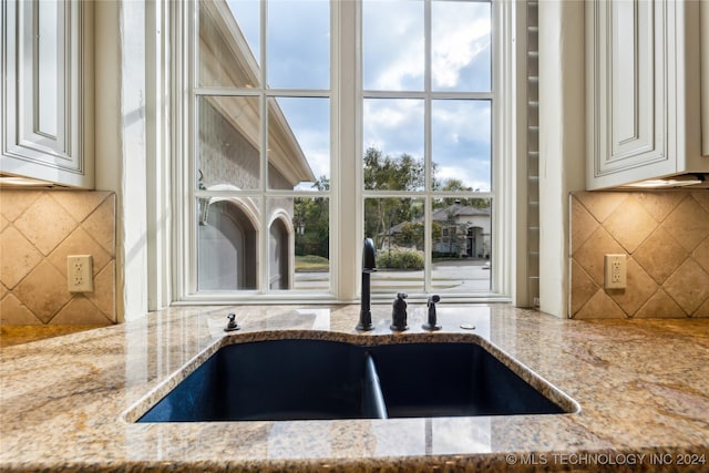 interior space featuring light stone counters, sink, and backsplash