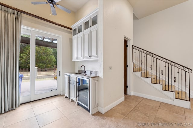 interior space featuring white cabinetry, wine cooler, light tile patterned flooring, and sink