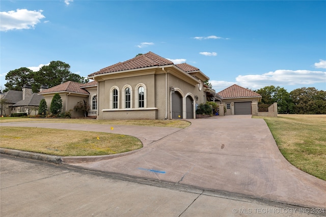 mediterranean / spanish home featuring a garage and a front lawn