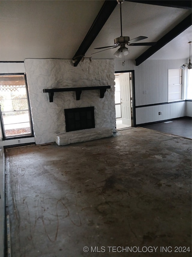 unfurnished living room with beam ceiling, a stone fireplace, and ceiling fan