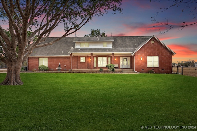 back house at dusk featuring a yard