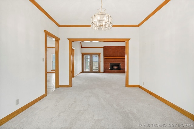 unfurnished living room featuring ornamental molding, an inviting chandelier, a brick fireplace, and light colored carpet