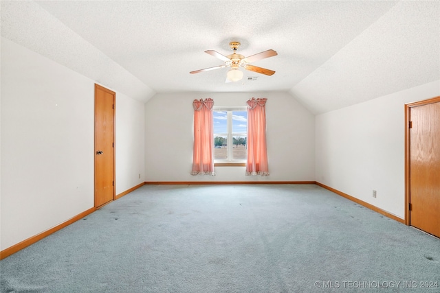 additional living space with vaulted ceiling, ceiling fan, a textured ceiling, and light colored carpet