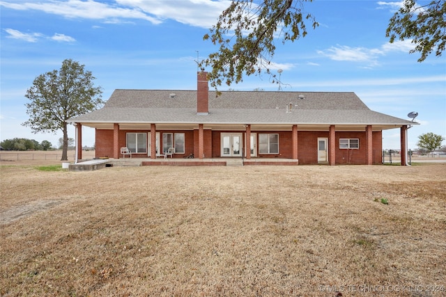 rear view of property featuring covered porch and a lawn