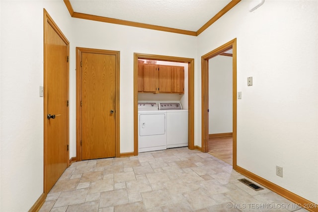 clothes washing area featuring crown molding, a textured ceiling, cabinets, and washer and clothes dryer