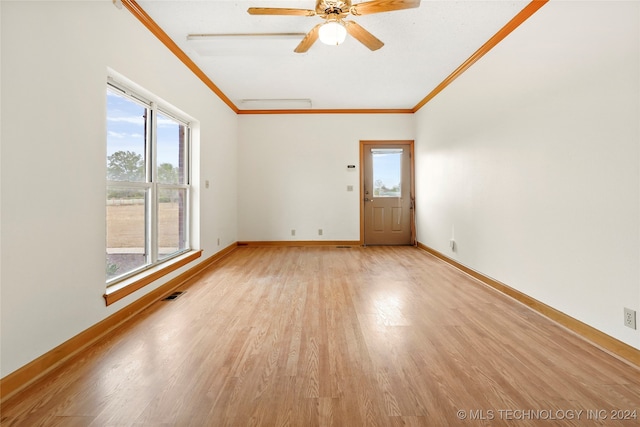 spare room featuring crown molding, light wood-type flooring, and plenty of natural light