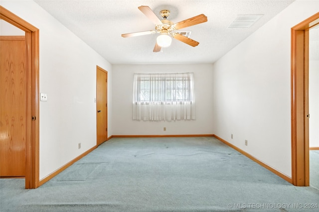 carpeted spare room with a textured ceiling and ceiling fan