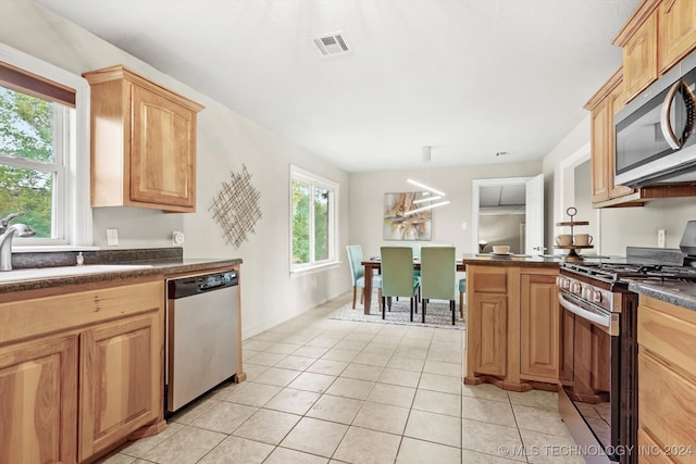 kitchen with appliances with stainless steel finishes, light tile patterned floors, pendant lighting, and light brown cabinets