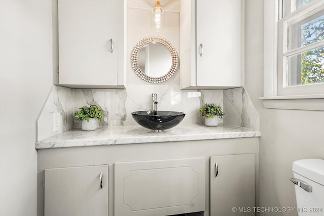 bathroom featuring vanity, toilet, and tasteful backsplash