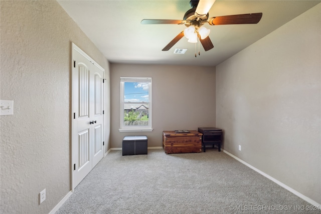 living area featuring light carpet and ceiling fan