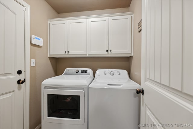 clothes washing area with washer and dryer and cabinets