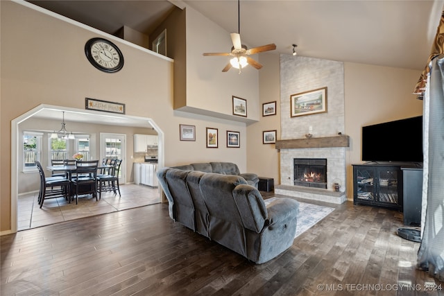 living room featuring a stone fireplace, hardwood / wood-style flooring, high vaulted ceiling, and ceiling fan