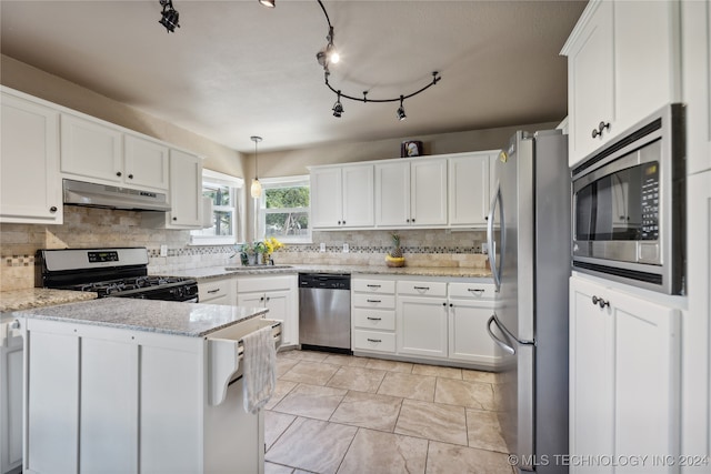 kitchen featuring white cabinetry, stainless steel appliances, hanging light fixtures, and light stone counters