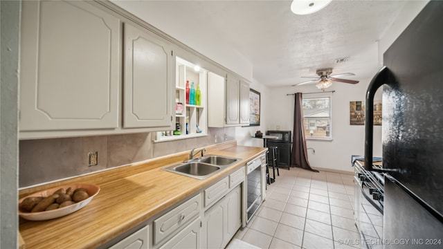 kitchen featuring light tile patterned floors, black fridge, dishwashing machine, stainless steel range, and sink