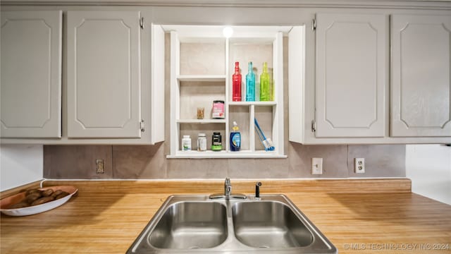 kitchen featuring wooden counters, sink, white cabinetry, and decorative backsplash