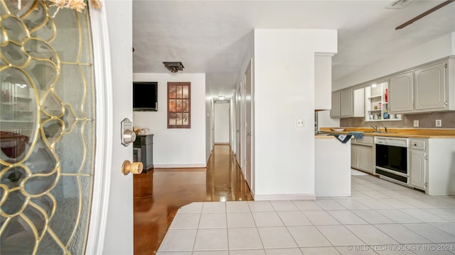 kitchen featuring gray cabinetry, dishwasher, sink, ceiling fan, and light tile patterned floors