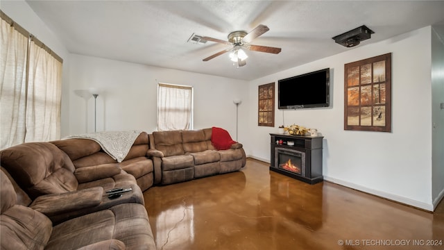 living room featuring ceiling fan, a textured ceiling, and a fireplace