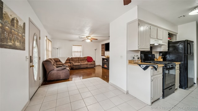 kitchen with white cabinetry, ceiling fan, light tile patterned floors, and black gas stove