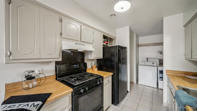 kitchen with wooden counters, black appliances, washing machine and clothes dryer, and light tile patterned floors