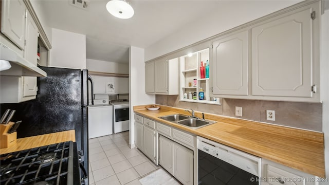 kitchen featuring backsplash, white dishwasher, sink, separate washer and dryer, and light tile patterned floors