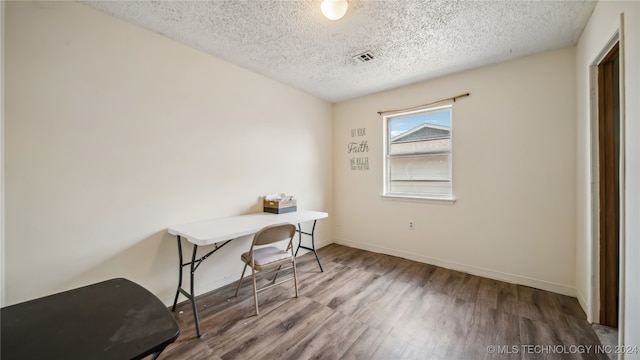 unfurnished office featuring hardwood / wood-style floors and a textured ceiling