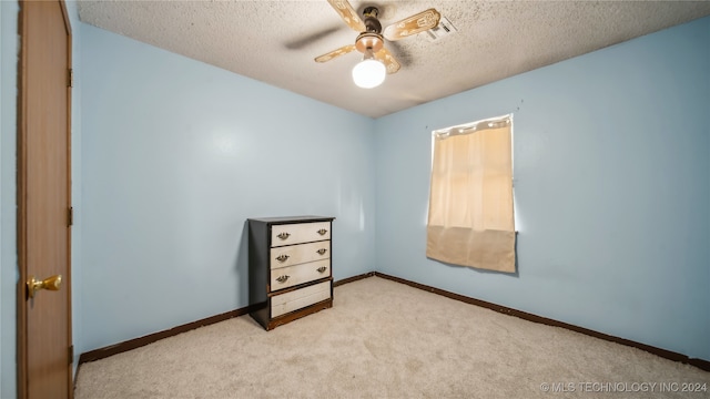 unfurnished bedroom featuring ceiling fan, light carpet, and a textured ceiling