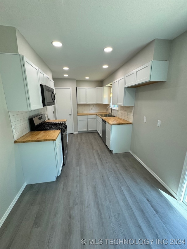 kitchen featuring wood counters, light hardwood / wood-style floors, stainless steel dishwasher, white cabinets, and gas range