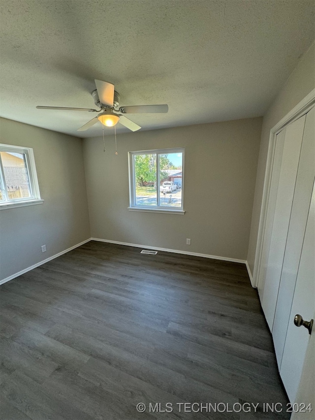 unfurnished bedroom featuring dark hardwood / wood-style flooring, a closet, a textured ceiling, and ceiling fan