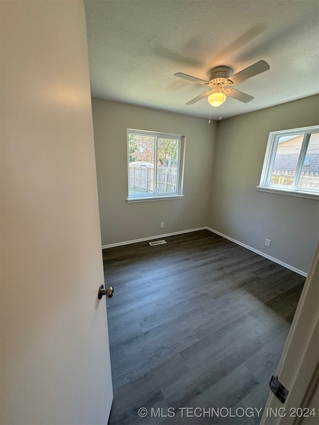 spare room with a textured ceiling, dark wood-type flooring, and ceiling fan