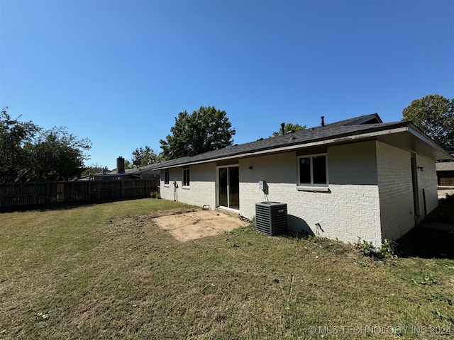 rear view of property featuring central AC and a lawn