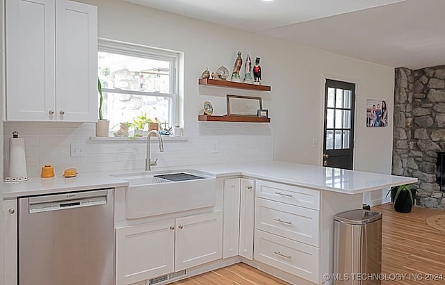 kitchen featuring light hardwood / wood-style floors, white cabinets, kitchen peninsula, sink, and stainless steel dishwasher