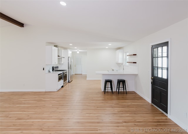 kitchen with kitchen peninsula, a breakfast bar, white cabinetry, light wood-type flooring, and appliances with stainless steel finishes