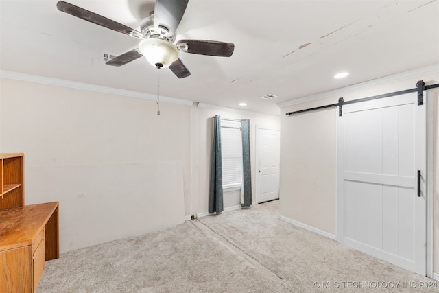 carpeted spare room featuring crown molding, a barn door, and ceiling fan