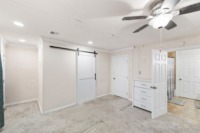 unfurnished bedroom featuring ceiling fan, light carpet, crown molding, and a barn door