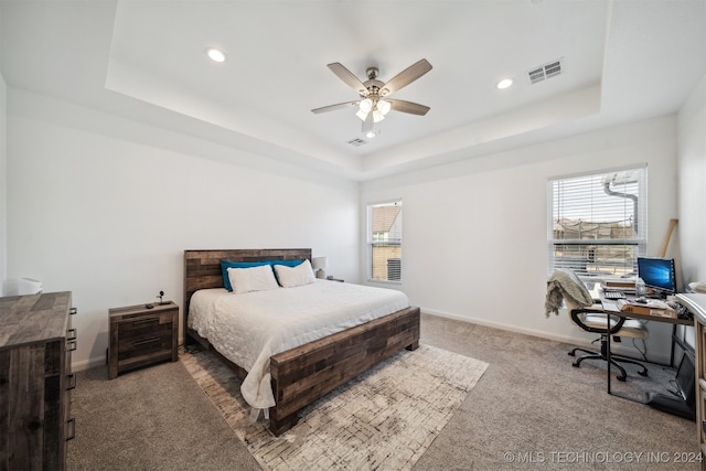 carpeted bedroom with ceiling fan and a tray ceiling