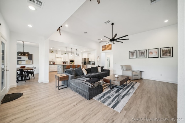 living room featuring ceiling fan with notable chandelier and light wood-type flooring