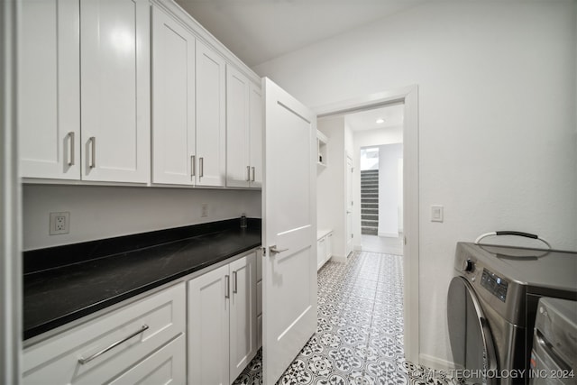 washroom with washer and dryer, light tile patterned floors, and cabinets