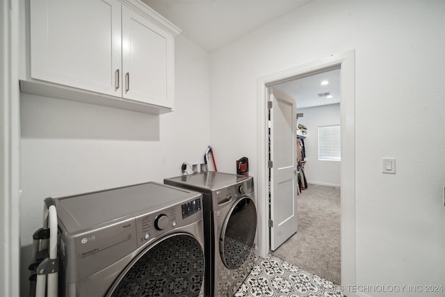 washroom with cabinets, light carpet, and washer and clothes dryer