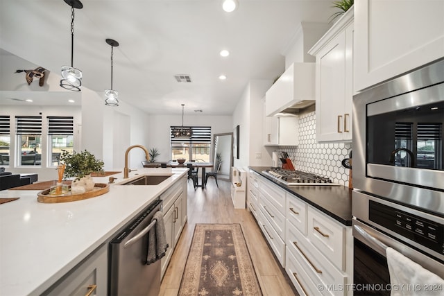 kitchen with pendant lighting, sink, white cabinetry, and stainless steel appliances