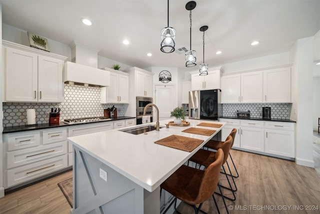 kitchen with sink, decorative light fixtures, light wood-type flooring, and stainless steel appliances