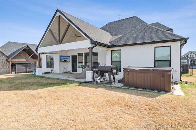 rear view of property featuring a patio, a hot tub, and a lawn