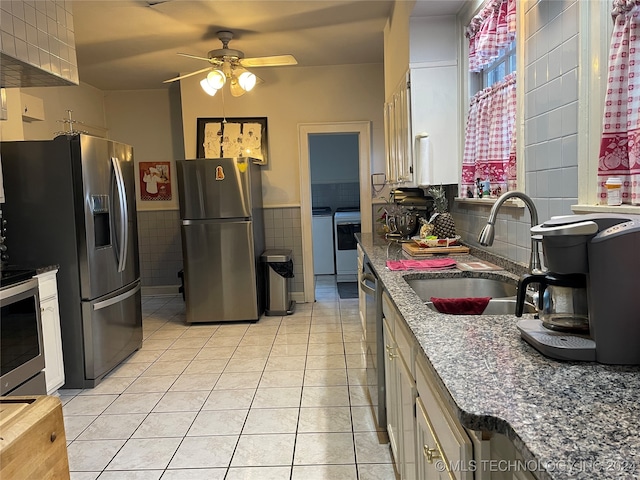 kitchen with tile walls, light tile patterned flooring, appliances with stainless steel finishes, sink, and independent washer and dryer