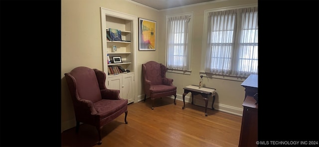 sitting room with built in features, light hardwood / wood-style flooring, and crown molding