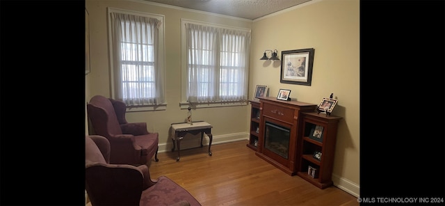 living area with light hardwood / wood-style flooring and crown molding