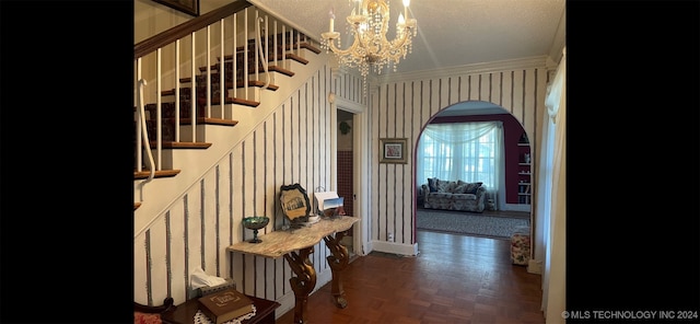 interior space featuring dark parquet flooring, an inviting chandelier, a textured ceiling, and ornamental molding