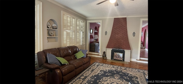 living room featuring crown molding, a textured ceiling, a wealth of natural light, a large fireplace, and ceiling fan