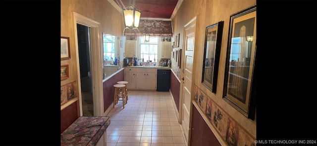 hallway featuring light tile patterned floors, crown molding, and an inviting chandelier