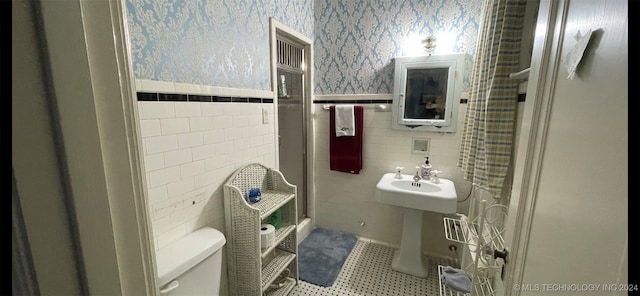 bathroom featuring walk in shower, tile patterned floors, toilet, and tile walls