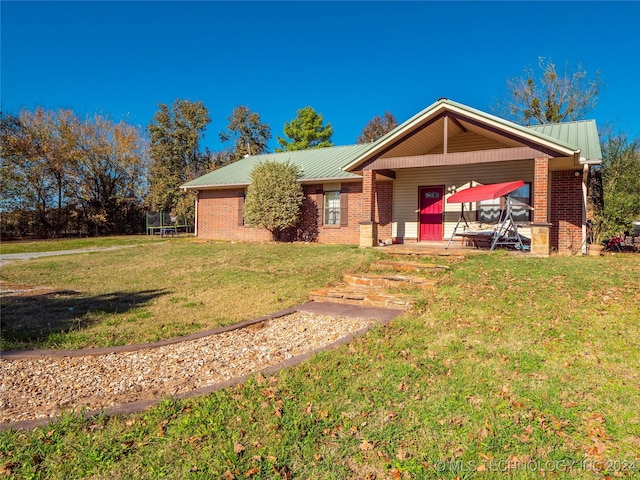 single story home featuring a front yard, brick siding, and metal roof